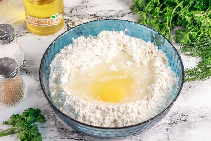 В глубокую емкость всыпьте пшеничную муку, оставив примерно четверть муки на раскатку, и сделайте в ней лунку. Вбейте туда куриное яйцо и всыпьте соль. Влейте холодную воду и замесите тесто.