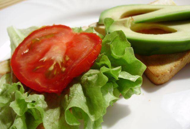 Уложите на один кусочек хлеба, смазанный майонезом тонко порезанный авокадо, а на другой - лист салата с помидорами.
