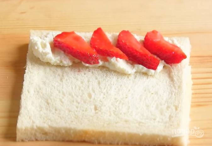 3. На край хлеба намажьте сладкий сырок и выложите нарезанную клубнику. 