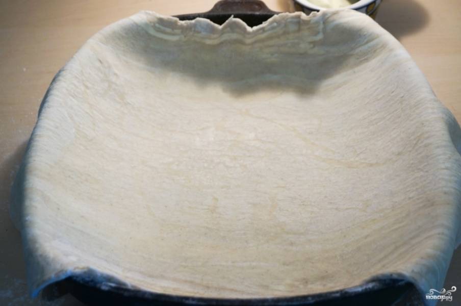 7. На присыпанной мукой поверхности раскатайте слоеное тесто примерно в два раза больше, чем форма. 