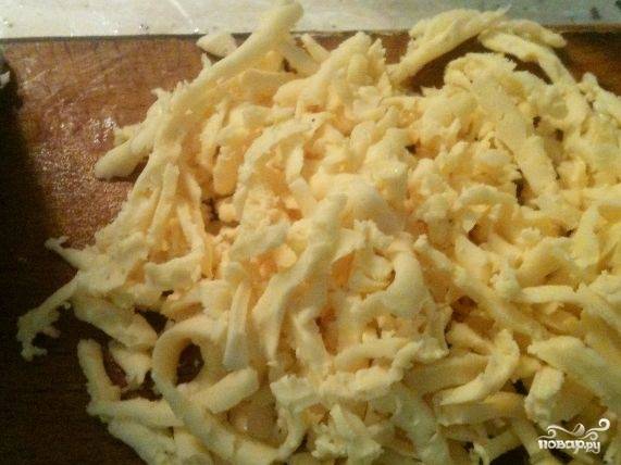 5. Натрите сыр на крупном полотне терки. Выложите его поверх слоя из жареного лука.