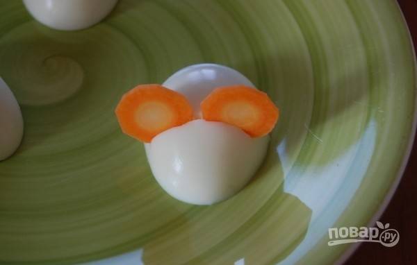 4.	На половинках яиц сделайте небольшие насечки и вставьте круглые ломтики моркови.