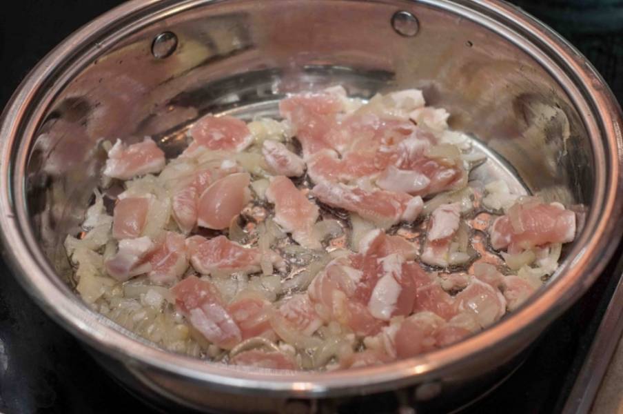 Разогрейте в сотейнике оливковое масло и обжарьте на нем лук и чеснок. Затем добавьте куриную грудку, готовьте еще 5 минут.