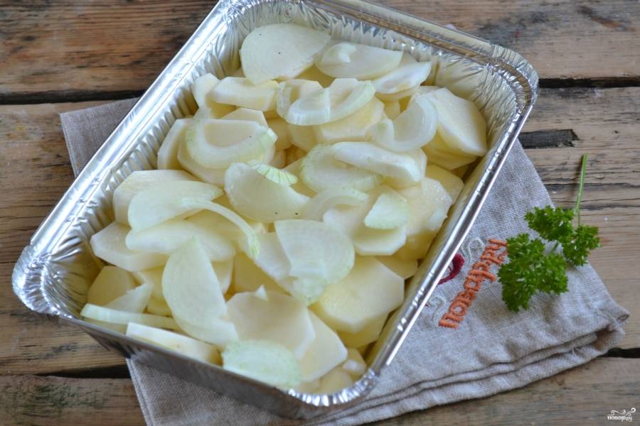 Обсушенный картофель нарежьте тоненькими кружочками. Лук разрежьте пополам и порежьте полукольцами. Форму для запекания застелите фольгой и смажьте сливочным маслом, начинайте выкладывать в неё овощи. Слой картофеля чередуйте с луком. Обязательно присаливайте, чтобы готовое блюдо не получилось пресным.