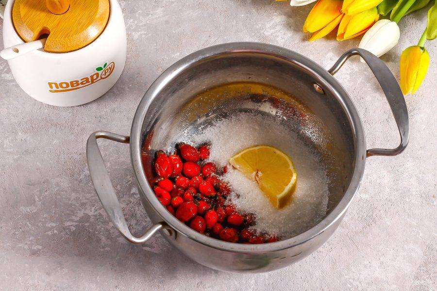 Всыпьте ягоды в кастрюлю или ковш. Туда же добавьте сахарный песок и ломтики лимона.