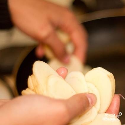 1. Картошку очистите, промойте и нарежьте пластинками вдоль. В сковороду влейте масло и нагрейте на среднем огне. Выложите в сковороду нарезанный картофель.
