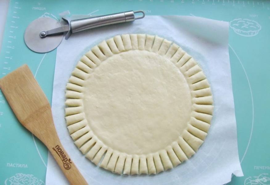 На тесто выложите тарелку, оставляя край шириной 3-4 сантиметра. Получается ободок, который нужно нарезать полосками шириной 1 сантиметр.