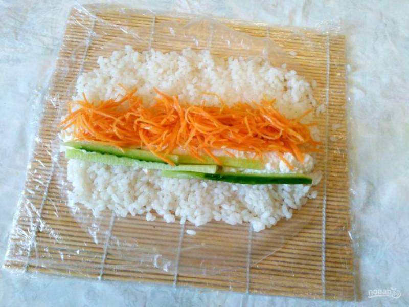 В центре смоченного рисового листа разместите вторую половину риса, а затем - все составляющие вегетарианской начинки.