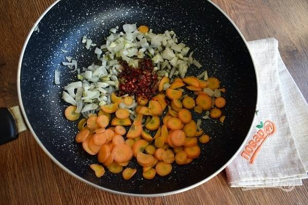 На сковороде разогрейте масло. Лук измельчите, молодую морковь нарежьте тонкими колечками. Лук, морковь и сушеный болгарский перец поместите на сковороду. Обжарьте овощи до золотистой корочки.