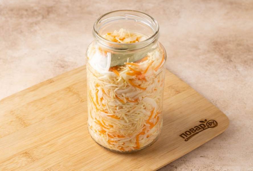 Плотно выложите капусту с морковью в банку. Добавьте лавровый лист и растительное масло.