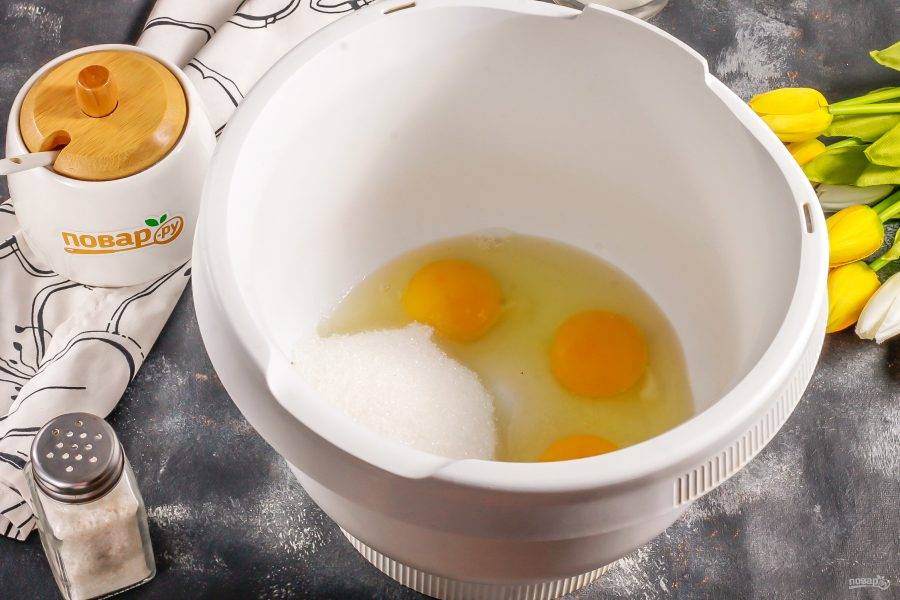 Куриные яйца вбейте в емкость миксера или чашу кухонного комбайна. Всыпьте туда же сахар и соль. По желанию можете добавить ванильный сахар. Взбейте все примерно 3-4 минуты в пышную пену.