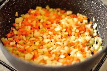 В глубокой сковороде греем 2 столовых ложки оливкового масла. Обжарьте лук, сельдерей и морковь. Жарить на медленном огне до мягкости.