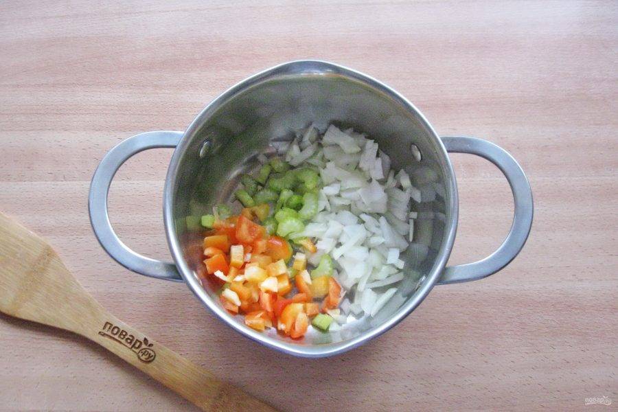Тем временем помойте и нарежьте сельдерей, болгарский перец, лук и чеснок. Выложите в кастрюлю с толстым дном. Налейте растительное масло и обжаривайте на среднем огне 7-8 минут перемешивая.