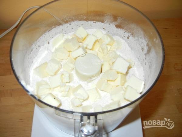 1. Первым делом нужно сделать тесто. В глубокую мисочку отправьте просеянную муку, сахар, щепотку соли и разрыхлитель. Перемешайте сухие ингредиенты и добавьте холодное сливочное масло. 