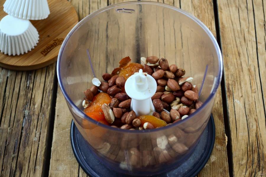 Курагу, грецкие орехи и арахис всыпьте в чоппер и измельчите до состояния крошки.