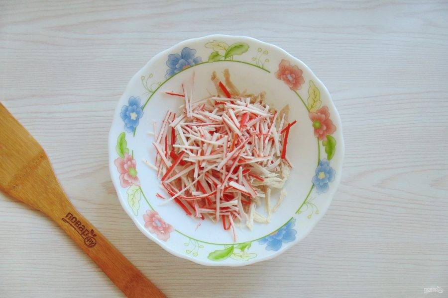 Крабовые палочки нарежьте тонкой соломкой. Добавьте к курице.