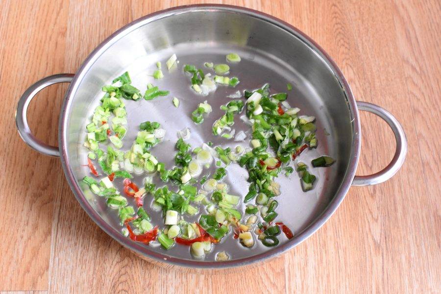 Промойте и обсушите зеленый лук, очистите имбирь и перец чили. Нашинкуйте все мелко и прогрейте в масле до появления яркого аромата. Нет нужды подрумянивать овощи.