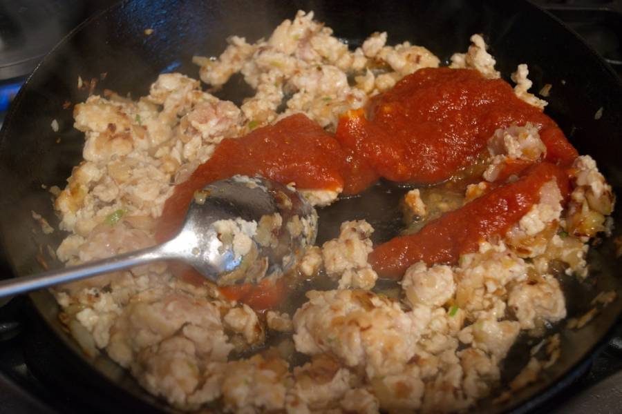 На сковороде обжарьте лук. Добавьте мясо. Быстро размешайте. Добавьте томатный соус. Тушите все, постоянно помешивая. Добавьте соль, специи.