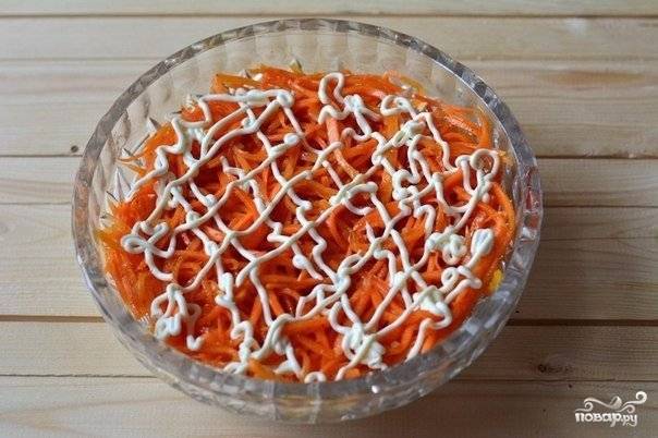 Поверх курицы выложите морковку по-корейски. Покройте второй слой майонезом.