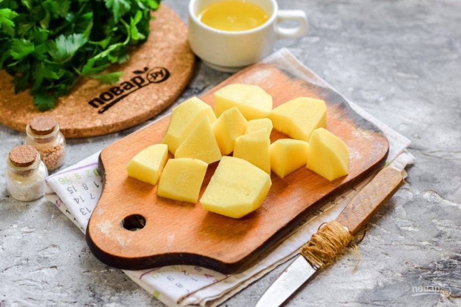 Клубни картофеля нарежьте небольшими кусочками. Прогрейте духовку и установите температуру 180 градусов.
