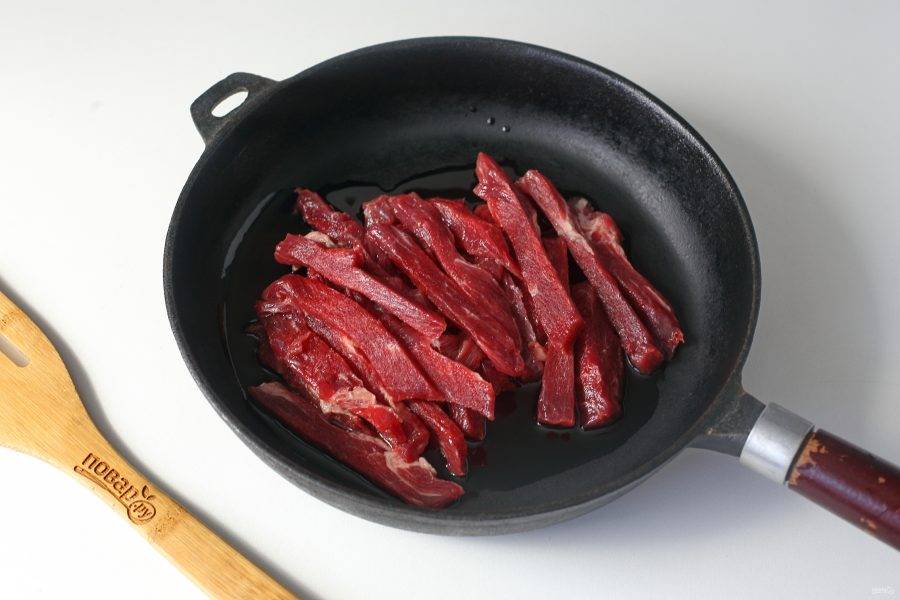 В сковороде нагрейте масло, и выложите говядину, нарезанную полосками.