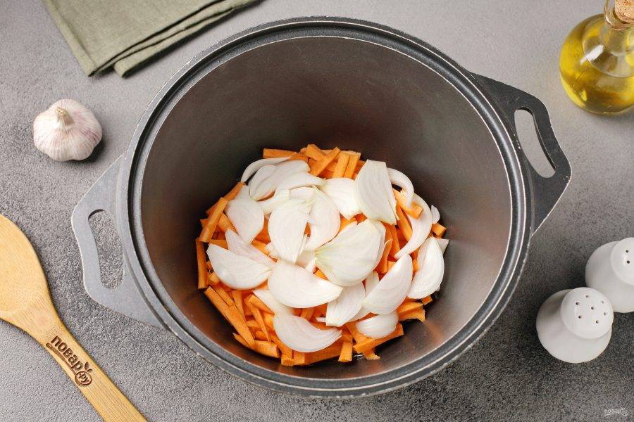 Разогрейте казан с маслом. Выложите нарезанную соломкой морковь и нарезанный перьями лук. 
