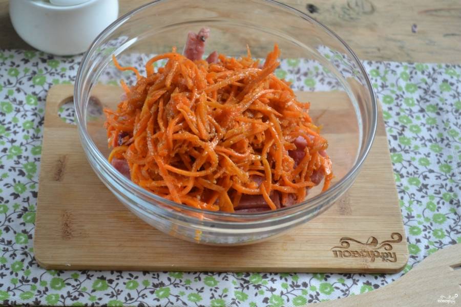 Сложите порезанную колбасу в салатник, добавьте к ней морковку. Если вам кажется, что морковь чересчур длинная, можете её немного порезать.
