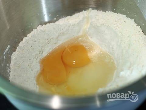 Для теста: в чашу миксера просейте муку, добавьте соль, дрожжи, сахар. В центр вбейте 2 яйца.
