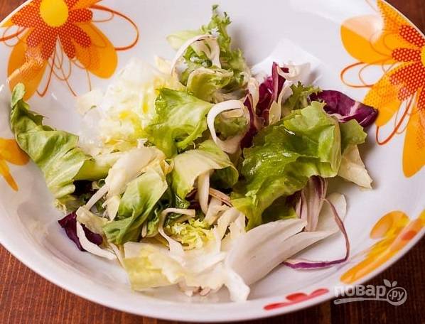2. На тарелку для подачи выложите любимые листья салата. Оливковое масло соедините с соком половины лимона, солью и перцем. Перемешайте и полейте зелень. 