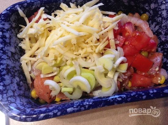 Выкладываем в форму для запекания рыбу с креветками и овощами, добавляем лук-порей, нарезанный кубиками помидор и половину натертого сыра. Перемешаем.