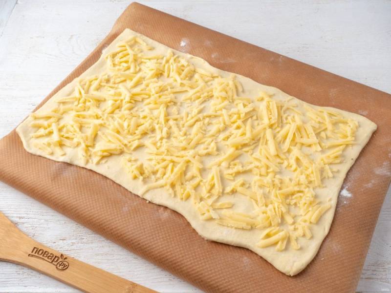 На крупной терке натрите сыр и ветчину. Сначала на тесто выложите сыр.