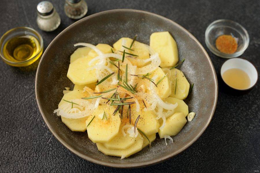 Нарежьте картофель кружочками толщиной 3-4 миллиметра, добавьте к нему нарезанный полукольцами лук и тонкими слайсами чеснок, а так же розмарин. Влейте ложку растительного масла, всыпьте соль, перец по вкусу и любимую приправу. Тщательно все перемешайте.