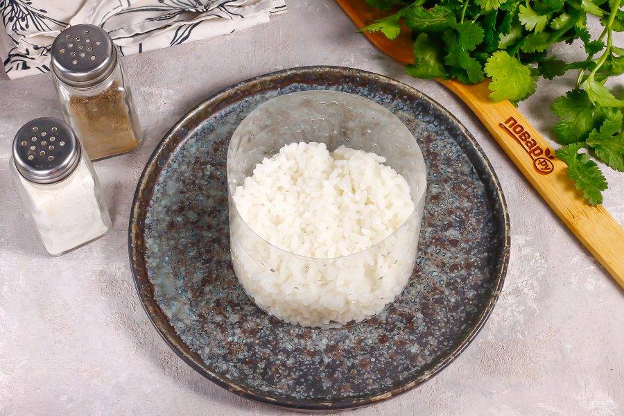 С помощью формировочного кольца или кольца, срезанного с пластиковой бутылки, выложите рис на тарелку, слегка прижимая его. Первый слой риса делайте широким.