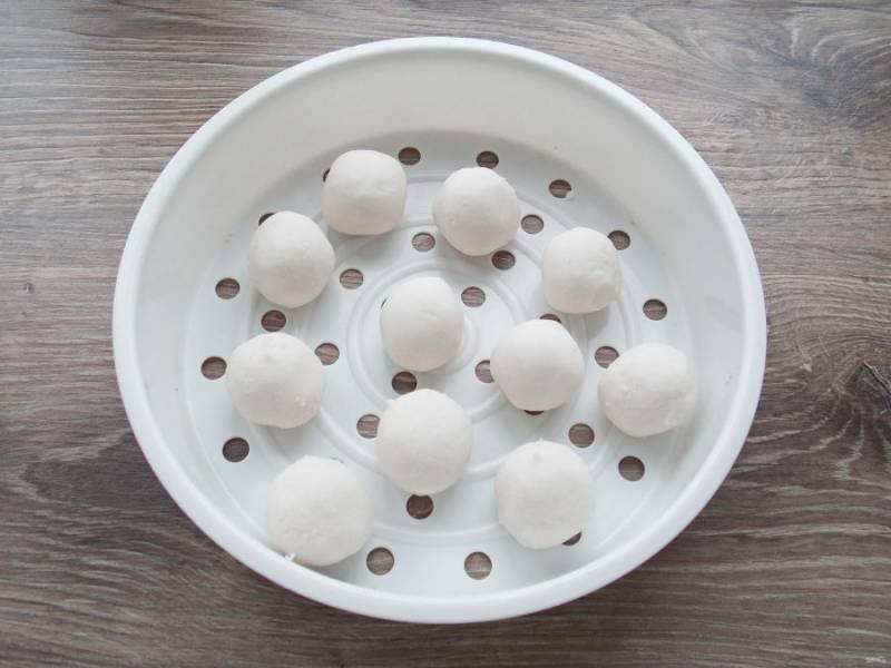 Из рисового теста скатайте шарики чуть меньше грецкого ореха и выложите на решетку для приготовления на пару. При желании можно смазать решетку растительным маслом.