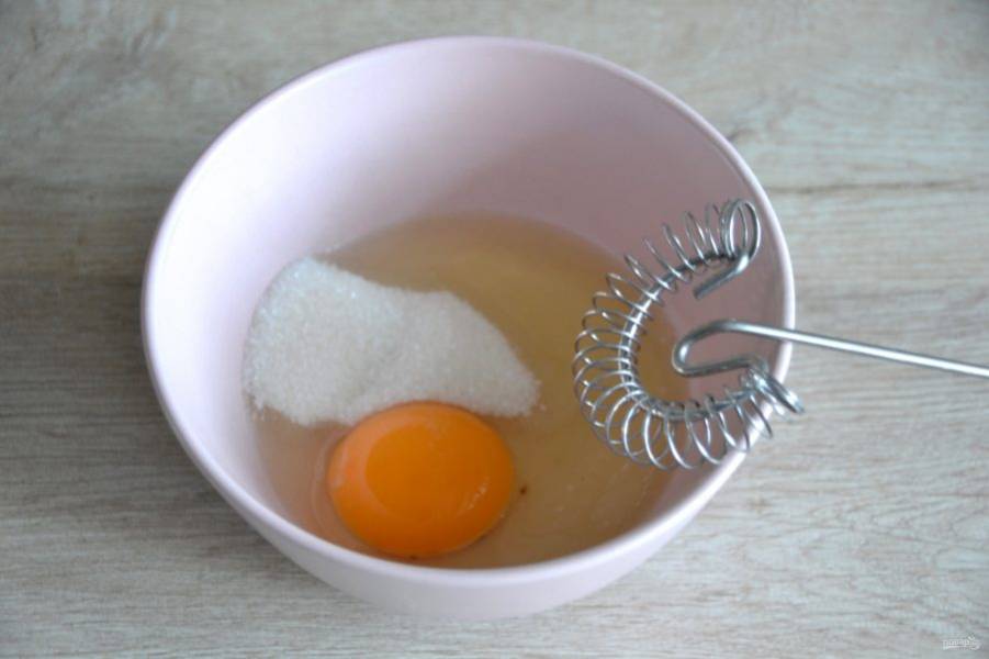 Для приготовления заварного крема смешайте яйцо и 1 ст. ложку сахара, всыпьте пакетик ванильного сахара.