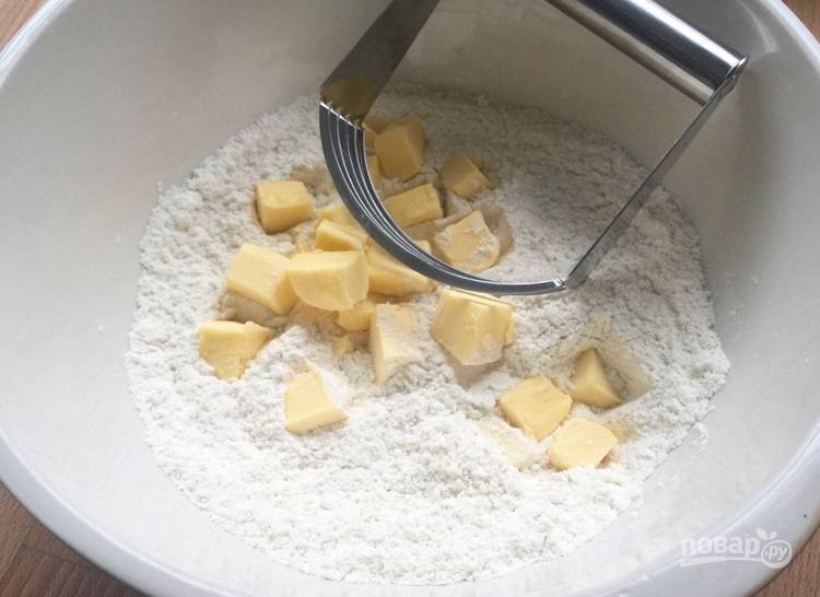 2. Холодное сливочное масло нарежьте кубиками и выложите в миску с сухими ингредиентами, разомните его в грубую крошку.