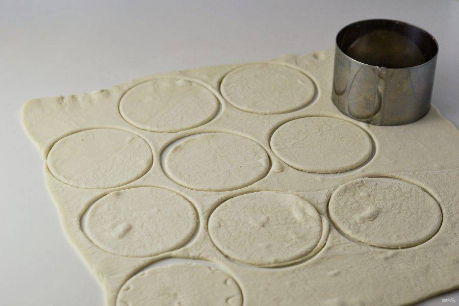 Разморозьте тесто. Раскатайте его толщиной 0,5 мм. Вырежьте с помощью рюмки или стакана кружочки. 
