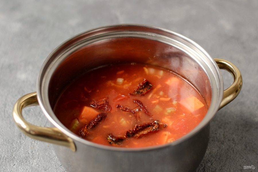 Влейте в кастрюлю томаты в собственном соку и овощной бульон, добавьте вяленые томаты. Доведите до кипения, убавьте температуру до минимума и варите суп 25-30 минут.