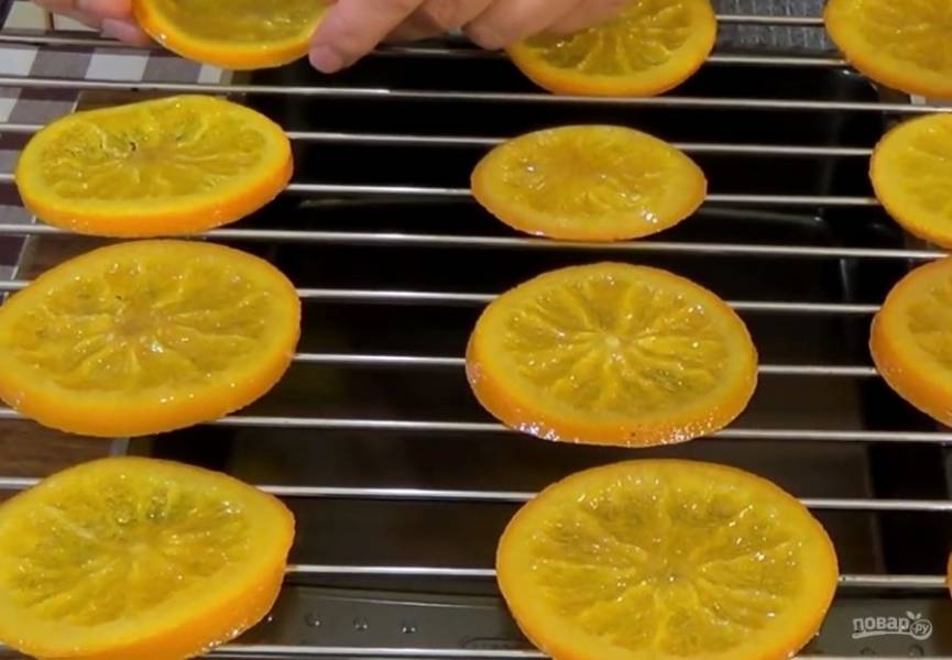 3. Выложите апельсины в дуршлаг и оставьте на 30 минут. Выложите дольки апельсина на решетку в один слой и отправьте в разогретую до 140 градусов духовку на 30 минут, предварительно установив застеленный бумагой для выпечки противень на нижний уровень духовки. 