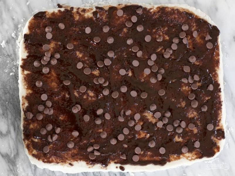 7.	Растопите сливочное масло, добавьте к нему коричневый сахар и корицу, смажьте приготовленной смесью тесто и посыпьте шоколадной стружкой.