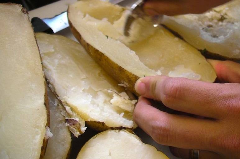 3. Ложкой выньте серединку, стараясь не повредить основу. Переложите картофельную мякоть в глубокую мисочку. 