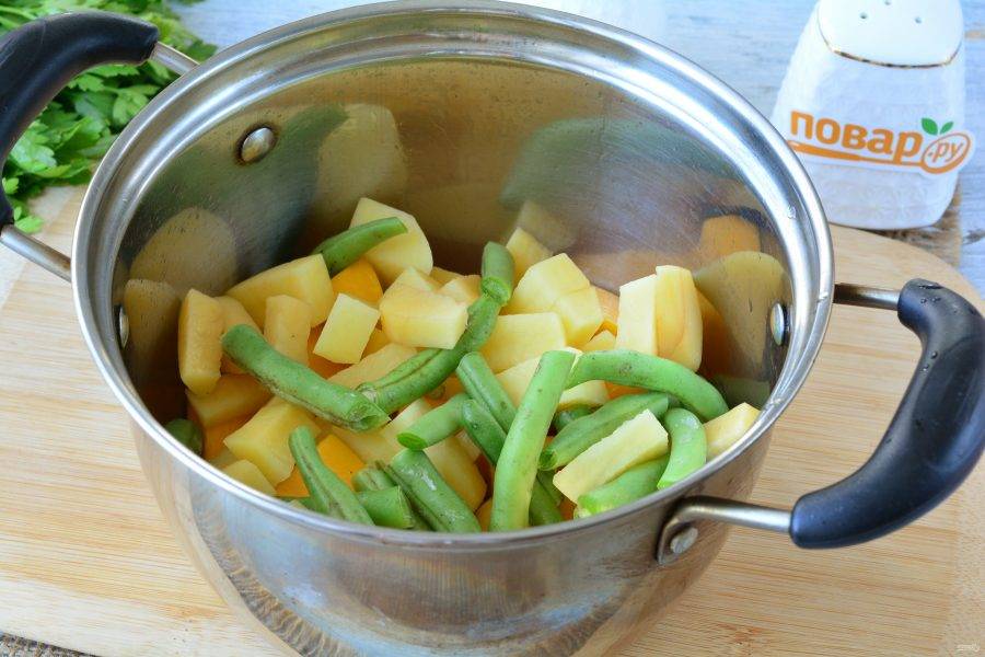 Всыпьте картофель и фасоль в кастрюлю, перемешайте и обжаривайте все овощи еще 3-4 минуты. Тыква уже станет мягче и будет ароматной.