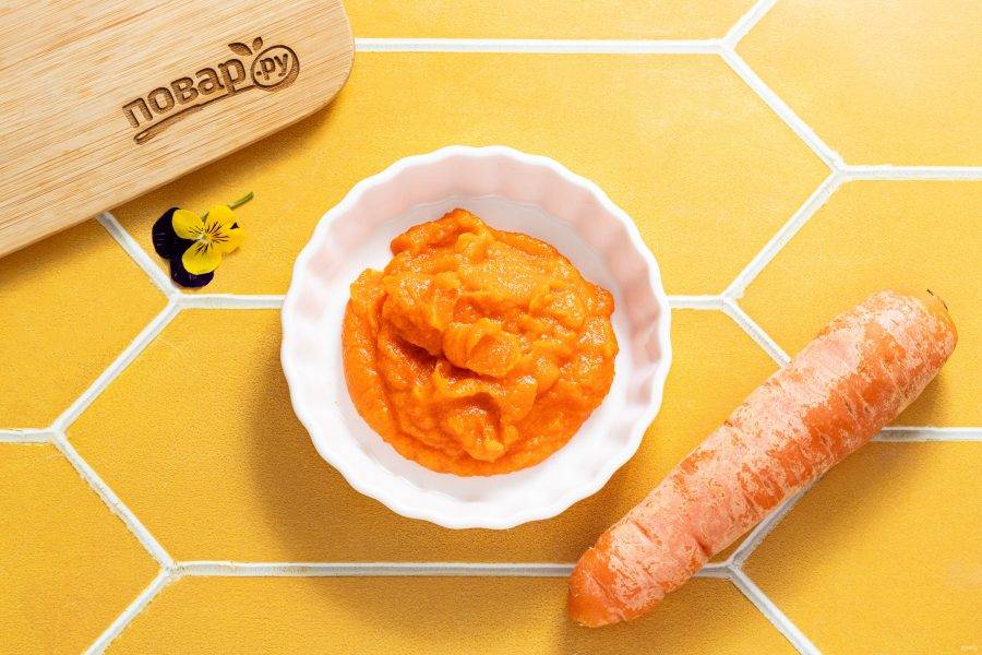 Морковь очистите от кожуры, нарежьте на маленькие кубики. Переложите в кастрюлю, влейте небольшое количество воды (около 75-80 мл.) и отварите до мягкости. После измельчите морковь вместе с водой, в которой она варилась, блендером до однородного пюре.