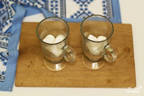 2.	В две чашки положите по 4 кусочка маршмеллоу (чашки лучше предварительно прогреть кипятком). Если зефир мелкий, возьмите по 8-10 кусочков на чашку.