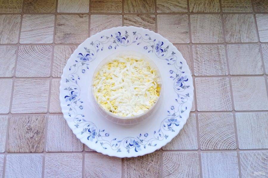 Яйца сварите вкрутую, охладите, очистите и натрите на терке. Выложите следующим слоем.