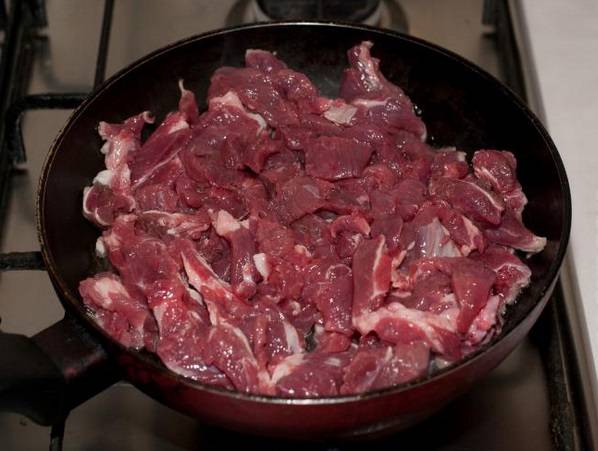 Сковородку разогреваем и наливаем в нее масло. Выкладываем мясо.