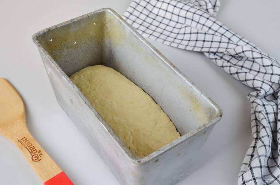 Смажьте форму для хлеба растительным маслом. Выложите тесто, накройте салфеткой и уберите в теплое место на 40 минут.
