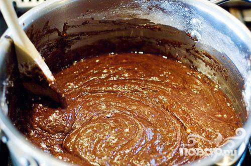 5. Пока пирог печется, приготовить шоколадную глазурь. Мелко нарезать орехи пекан. Растопить сливочное масло в кастрюле. Добавить какао, размешать и выключить огонь. Добавить молоко, ваниль и сахарную пудру. Перемешать.
