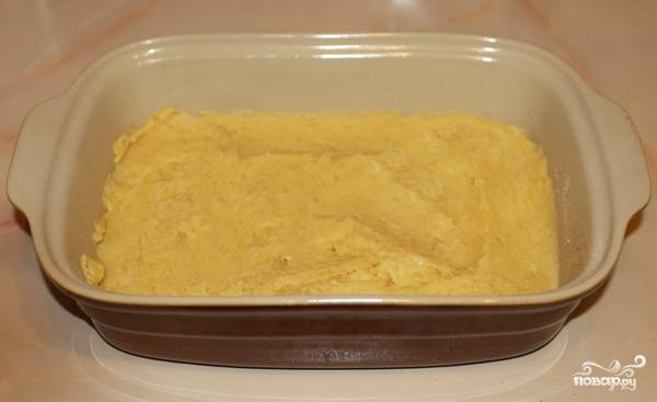 Чистим и варим картофель, разминаем его в пюре. Соединяем с яйцами и мукой. Перемешиваем. Форму для запекания смазываем маслом и обсыпаем панировочными сухарями. Выкладываем картофельную массу (меньше половины).