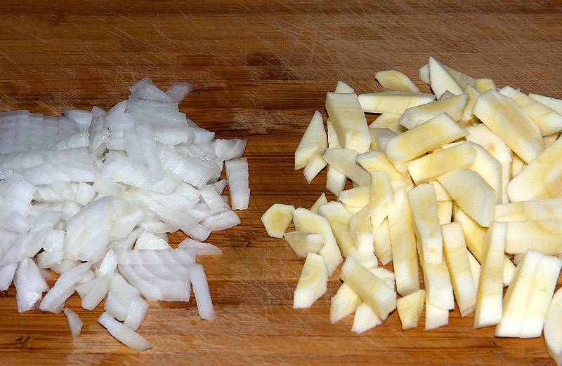 2. Очистить и нарезать мелким кубиком луковицу. Еще один ингредиент, который стоит использовать в рецепт приготовления капустного борща - это корень петрушки. Это тоже нарезать мелко. 